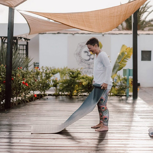 A student at Surya Yoga Retreat unrolls her mat on the yoga deck